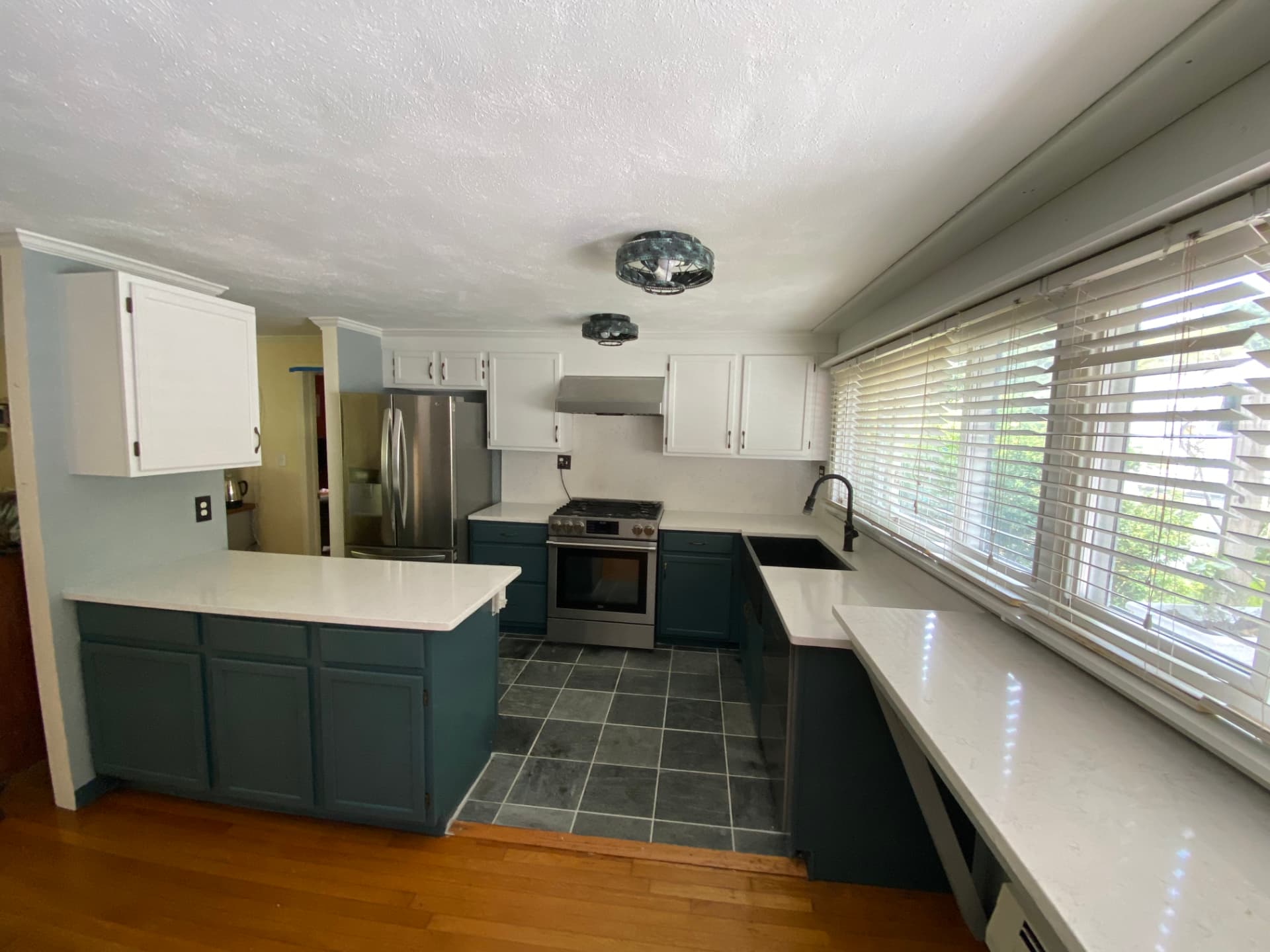 After: same Hull, MA kitchen with white upper cabinets and deep teal lower cabinets and peninsula