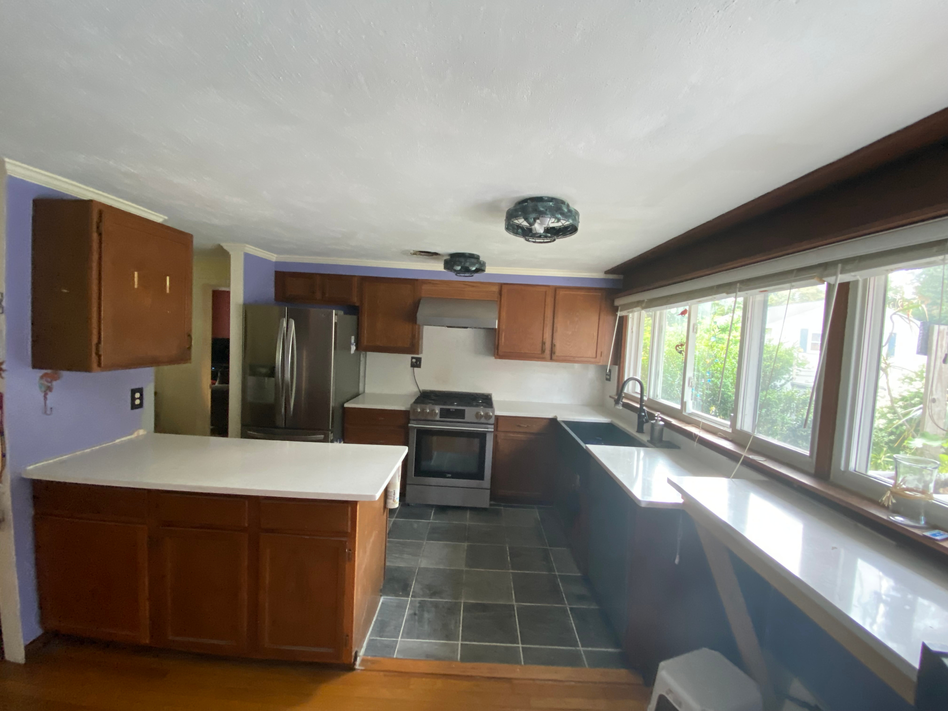 Before: Hull, MA kitchen with orange-stained oak cabinets, dark counters and purple walls